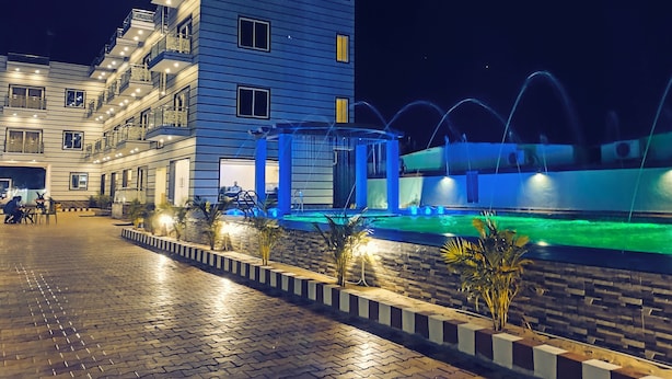 Un hotel de varios pisos con piscina y fuente.