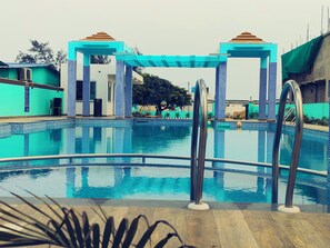 A swimming pool with a clear blue water surface, surrounded by a tiled deck and a metal pool ladder. - The Triton Beach Resort (Kanthi)