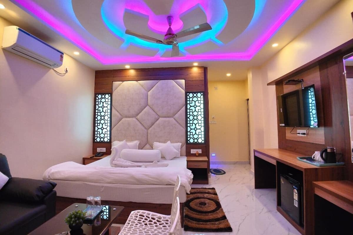 A modern hotel room with a bed, a desk, a TV, and a ceiling fan.