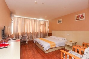 A hotel room with a bed, a desk, a chair, a TV, and curtains. - Huatai Express Chain Hotel (Wuxi)