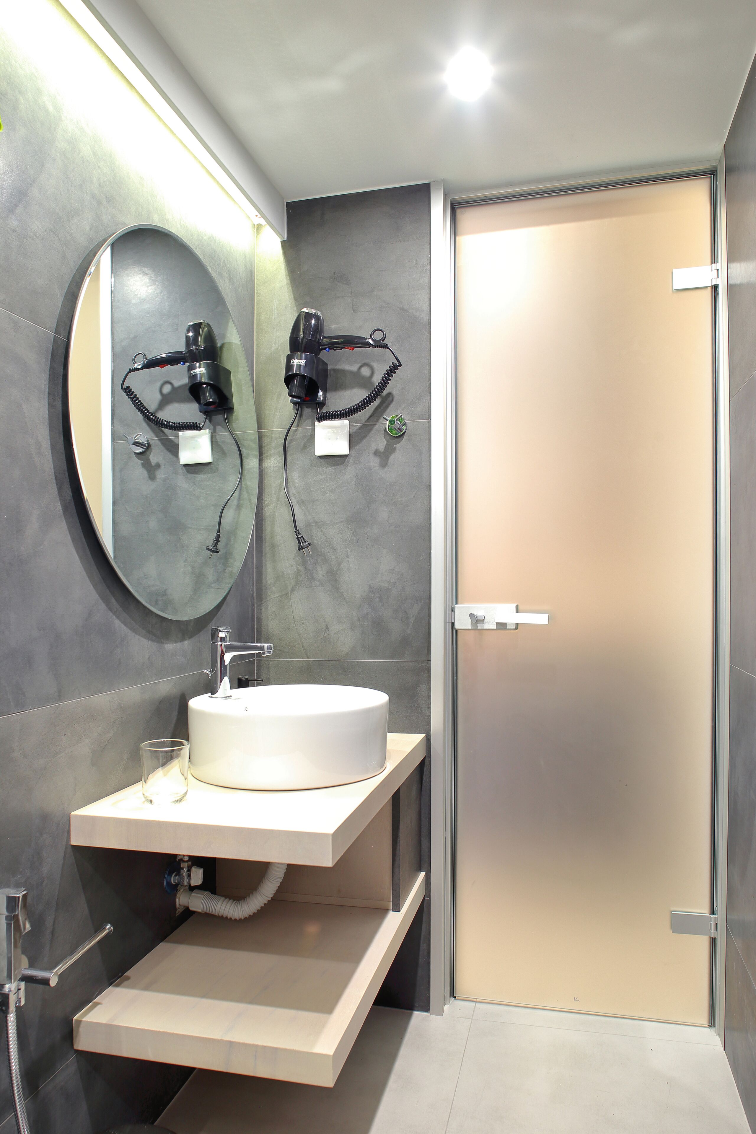 A modern bathroom with a large mirror, a sink, and a shower area.