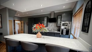Una cucina moderna con isola centrale, sgabelli da bar e un vaso di fiori.