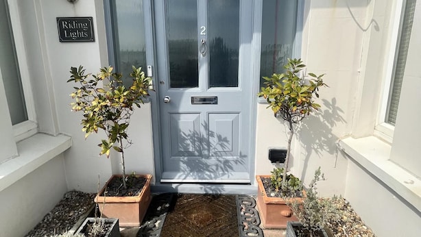 A front door with a number plate, two potted plants on either side, and a 'Riding Lights' sign on the wall. - Seaview 2 Bedroom House Sleeps 4 - Pets Ok -wifi (Shoreham-by-Sea)