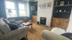 A living room with two sofas, a coffee table, a fireplace, and a television mounted on the wall. - Seaview 2 Bedroom House Sleeps 4 - Pets Ok -wifi (Shoreham-by-Sea)