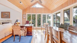 A spacious room with a wooden ceiling, a large window, a bed, a desk, and a dining area. - Gorgeous Quiet Lakefront Beach Cottage Inside Wild Dunes! (Isle Of Palms)
