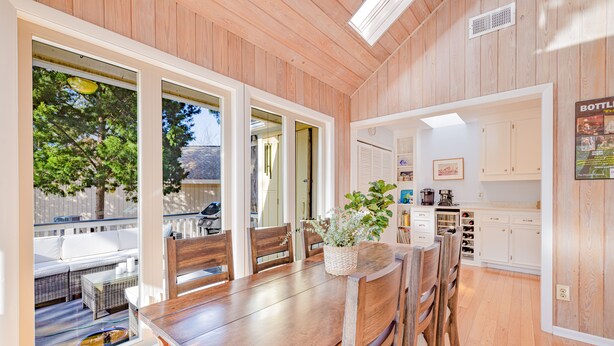 A dining area with a wooden table and chairs, a potted plant, and a view of the outdoors. - Gorgeous Quiet Lakefront Beach Cottage Inside Wild Dunes! (Isle Of Palms)