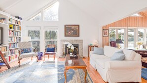 A spacious living room with a fireplace, a white sofa, a coffee table, and a bookshelf. - Gorgeous Quiet Lakefront Beach Cottage Inside Wild Dunes! (Isle Of Palms)