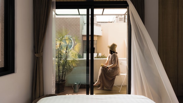 A room with a bed, a window with curtains, a potted plant, and a chair outside. - June June House (Tainan)