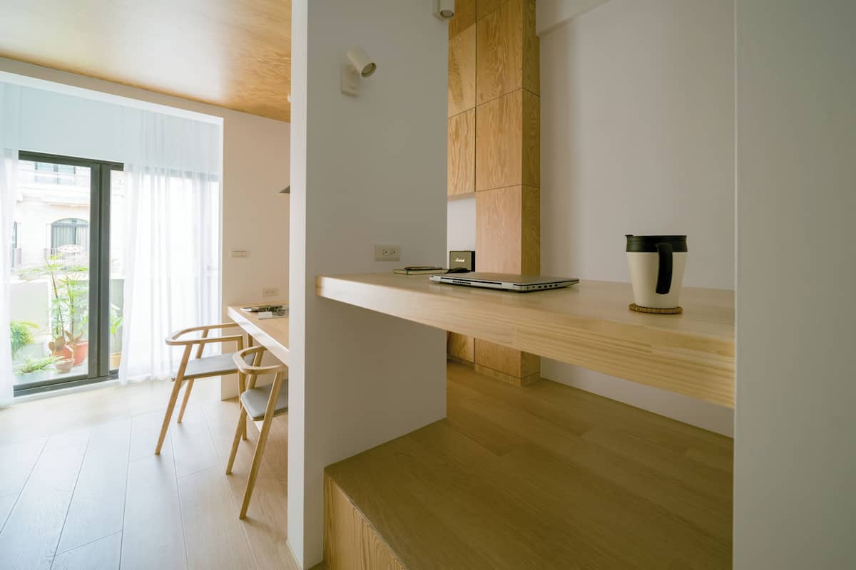 A modern kitchen with wooden cabinetry, a laptop on a countertop, and a coffee maker.