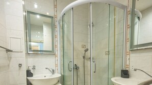 A modern bathroom with a glass-enclosed shower, two sinks, and a large mirror.