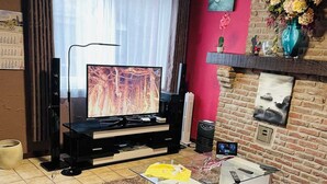 Uma sala de estar com televisão de tela plana sobre um suporte preto, uma mesa de centro de vidro e dois sofás de couro.