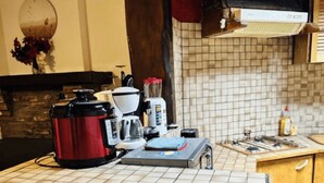 Uma cozinha com bancada revestida de azulejos, cafeteira, liquidificador e chaleira.