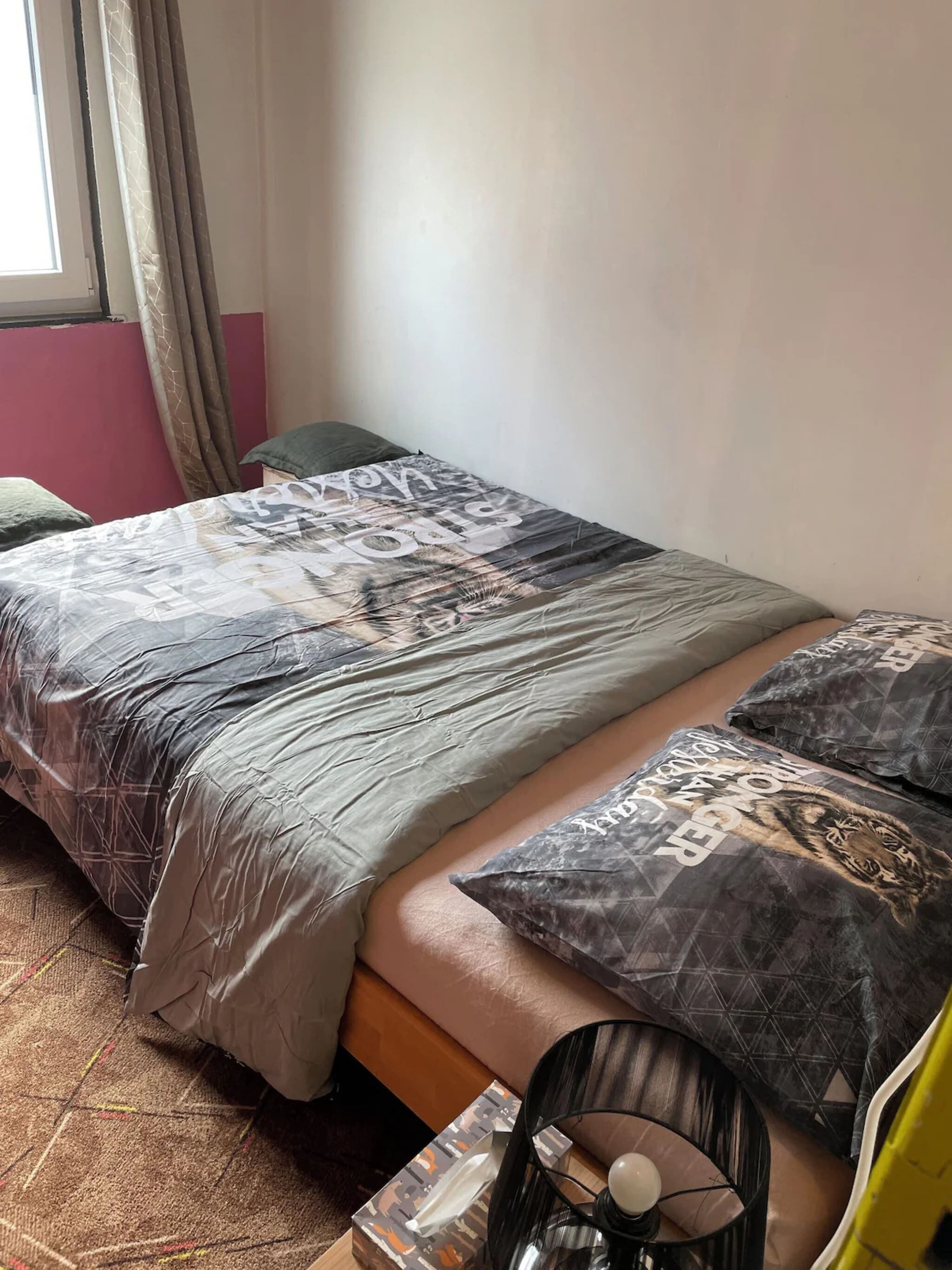 Een bed met decoratieve beddengoed, een nachtkastje en een lamp.