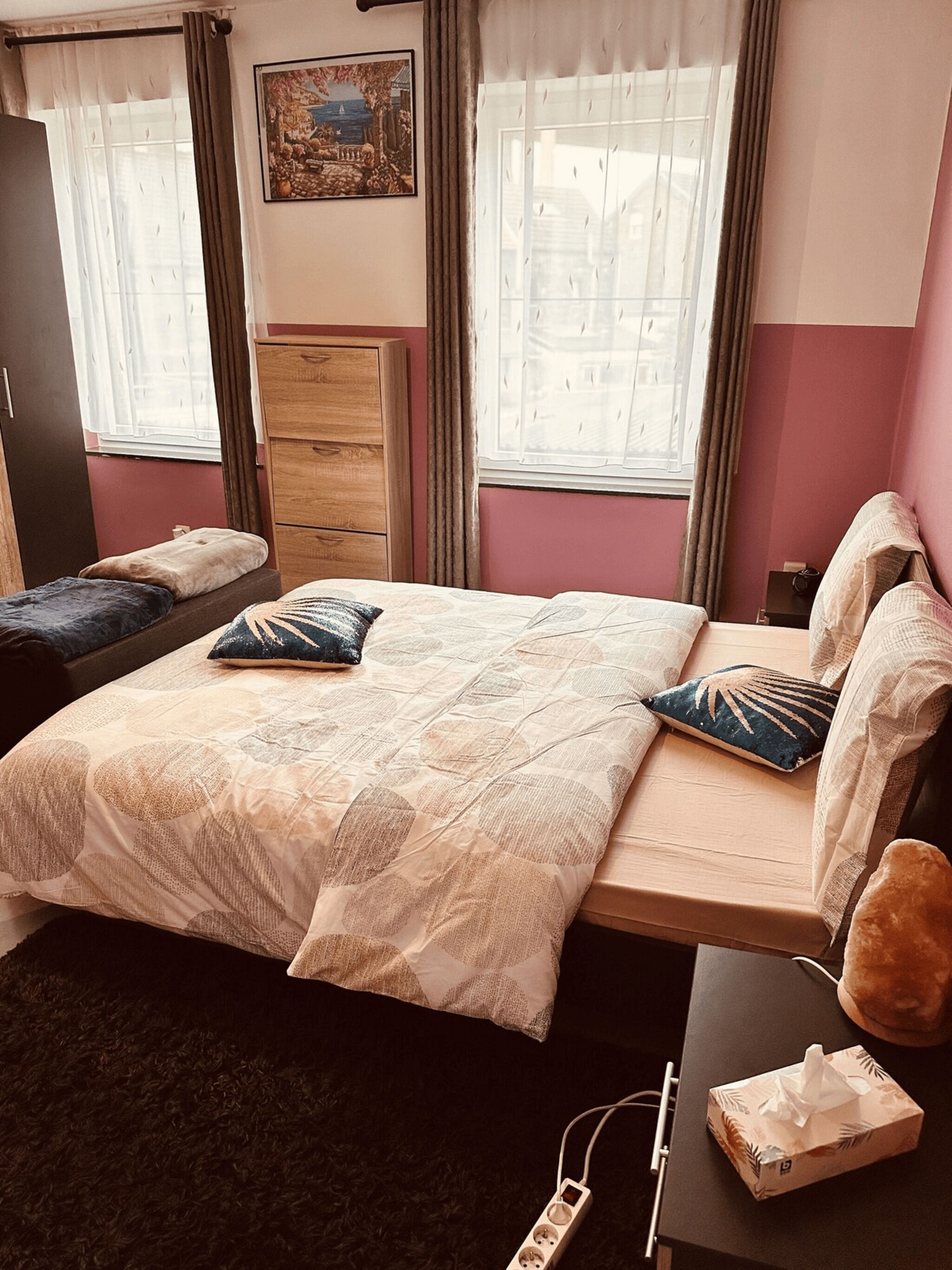 A bedroom with a bed, bedside tables, a dresser, and a window with curtains.