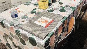 Mesa de jantar com toalha estampada, um centro de mesa decorativo e uma garrafa de água.