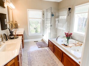 A modern bathroom with a large bathtub, a glass-enclosed shower, and a vanity with a sink. - Elegant Stonegate Home (Evans)