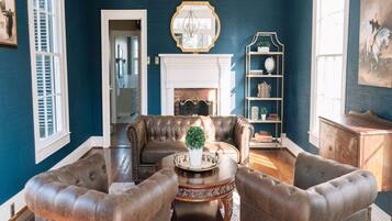 A room with a blue wall, a fireplace, a chandelier, and leather furniture.