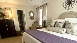 A bedroom with a bed, a dresser, a mirror, a lamp, and a window with curtains. - Elegant Crofton Ranch (Augusta)