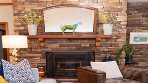 Un salon avec une cheminée en pierre, un canapé, une table basse et des plantes décoratives.