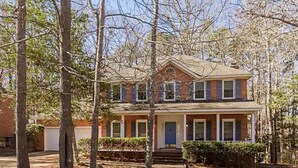 A two-story house with a front porch, a garage, and a well-maintained lawn.