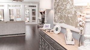 A spacious living area with a wooden coffee table, a decorative lamp, and a wall with a floral pattern.