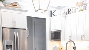 A modern kitchen with white cabinets, stainless steel appliances, and a marble island with bar stools.