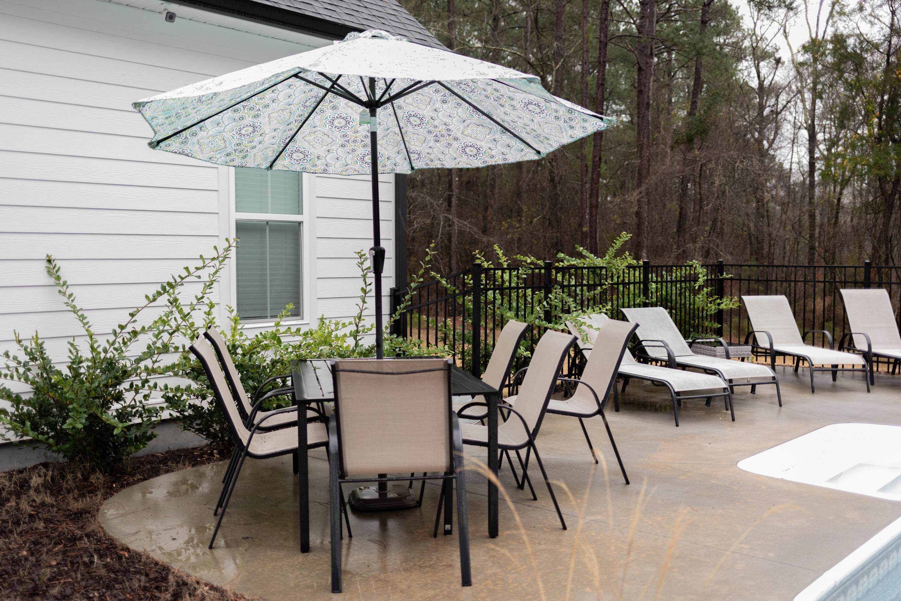 An outdoor patio with a pool, lounge chairs, and an umbrella.