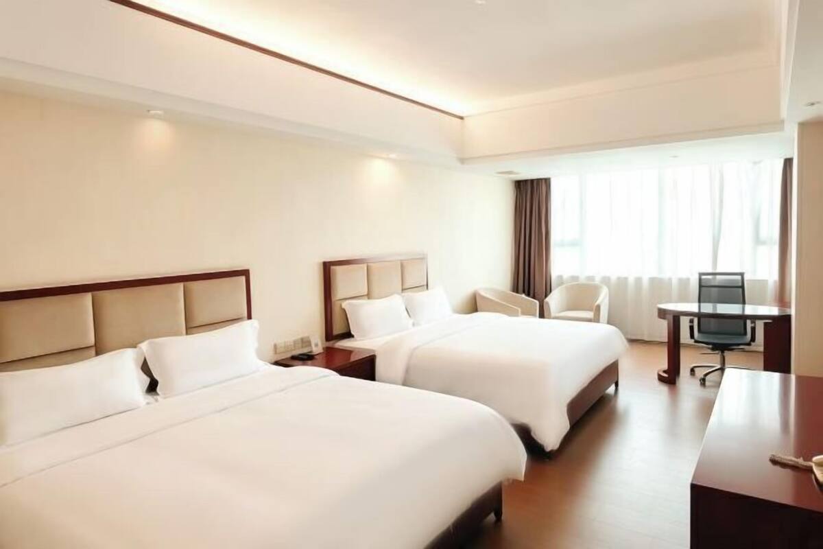 A hotel room with two beds, a desk, and a chair.