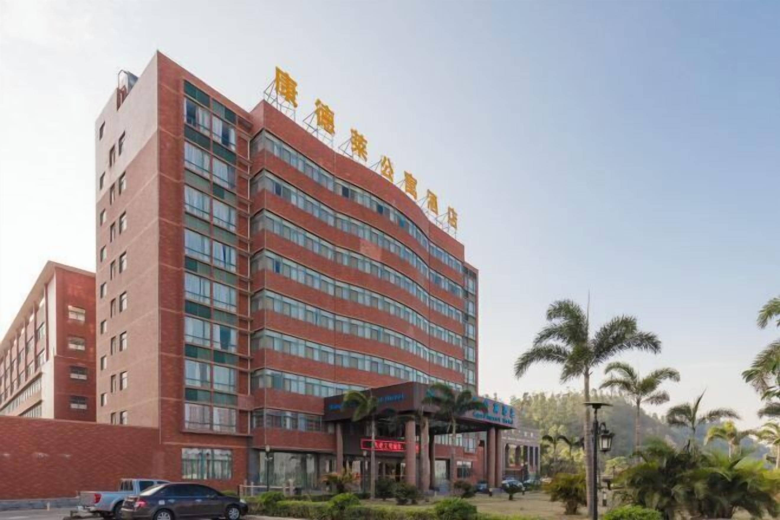 A multi-story hotel with a red brick facade and a sign in Chinese characters at the top.
