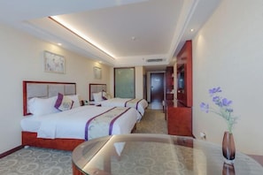 A hotel room with two beds, a glass table, and a vase with flowers.