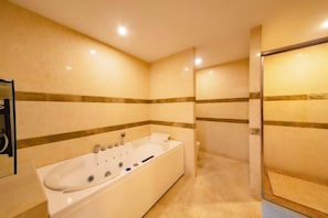 A modern bathroom with a large bathtub, a shower area, and a mirror.
