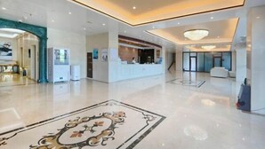 Un hall d’entrée spacieux, doté d’un sol ciré, d’un comptoir de réception et d’un grand tapis décoratif.