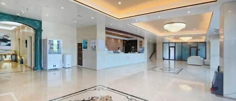 A spacious lobby with a polished floor, a reception desk, and a large decorative rug.
