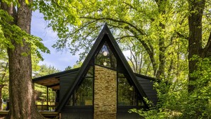 A cabin with a triangular roof, stone walls, and large windows. - Lake View Hot Tub Modern A-frame (Rockbridge)