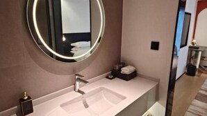 A modern bathroom with a round mirror, a single sink, and a small vanity area. - City Comfort Inn (Dali)