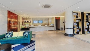 A hotel lobby with a reception desk, a sofa, a coffee table, and a bookshelf. - City Comfort Inn (Dali)
