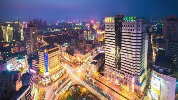 A nighttime cityscape with high-rise buildings, busy streets, and illuminated signage. - City Comfort Inn (Dali)