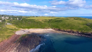 Un paysage côtier avec une plage, des falaises et un village situé au loin.
