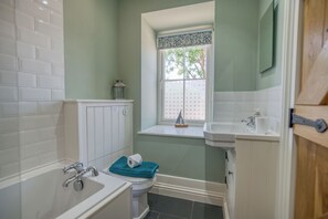 Une salle de bain avec une baignoire, des toilettes, un lavabo et une fenêtre donnant sur un beau paysage.