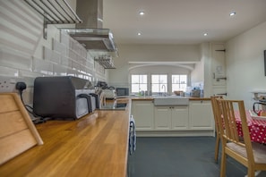 Une cuisine moderne avec des meubles blancs, un plan de travail en bois et un coin repas comprenant une table et des chaises.