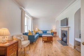 A living room with a sofa set, a fireplace, a television, and a lamp. - Ty Mor, Holiday Cottage Manorbier, Sleeps 8, 4 bedrooms,  bathrooms (Tenby)