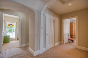 A hallway with a striped carpet, white doors, and a green dresser.