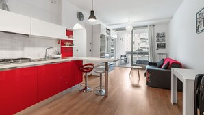 Eine moderne Küche mit roten Akzenten, ein Essbereich mit einer Couch und Blick auf die Stadt.