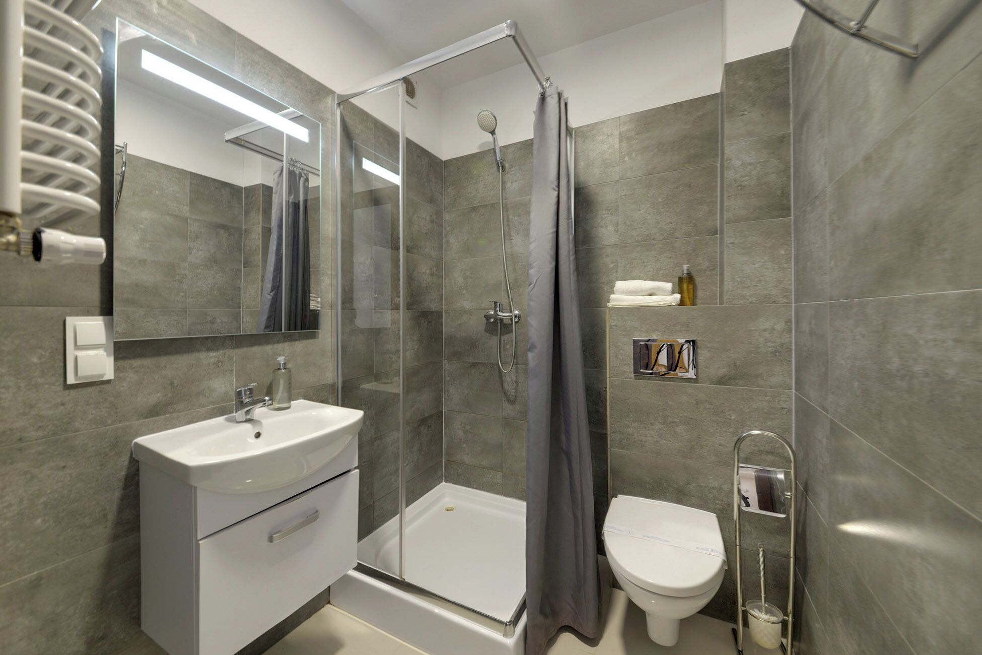 A modern bathroom with a glass shower enclosure, a white sink, and a toilet.