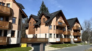 A row of multi-story buildings with balconies, a stone pathway, and a clear sky. - Apartamenty Sun & Snow Nad Łomnicą (Karpacz)