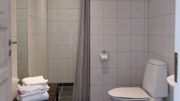 Een moderne badkamer met een douche, toilet en een handdoekrek met opgevouwen handdoeken.