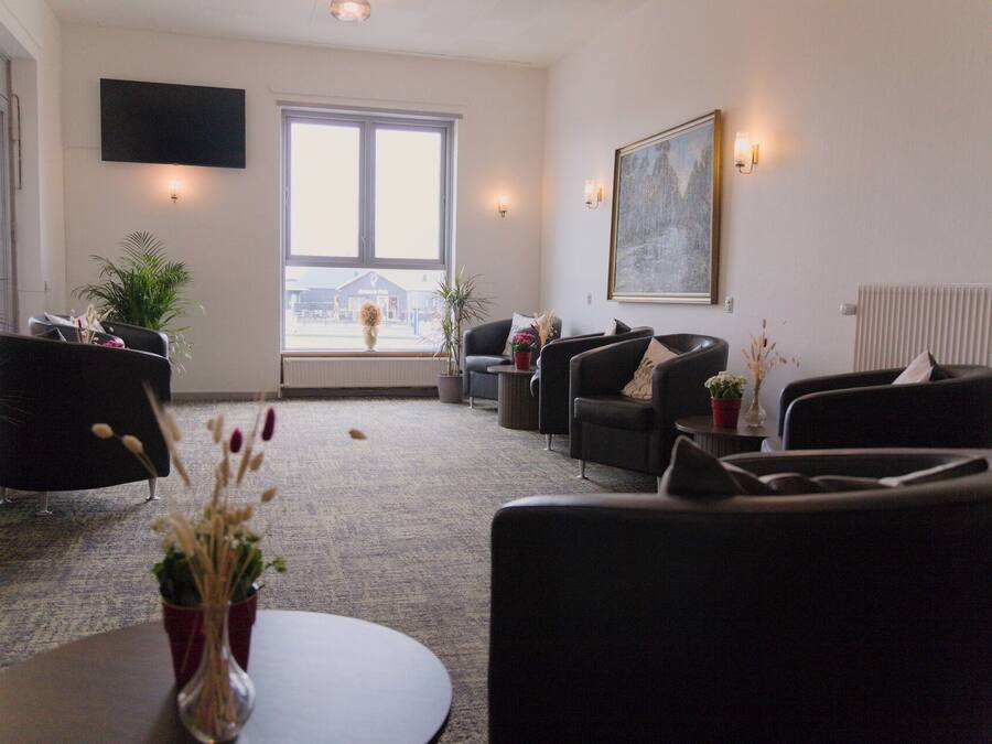 A modern living room with a large window, comfortable seating, and a flat-screen TV.
