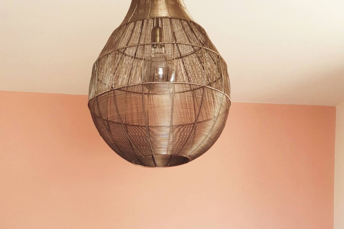 Une chambre avec un grand lit, une tête de lit en osier et deux ventilateurs fixés au mur.