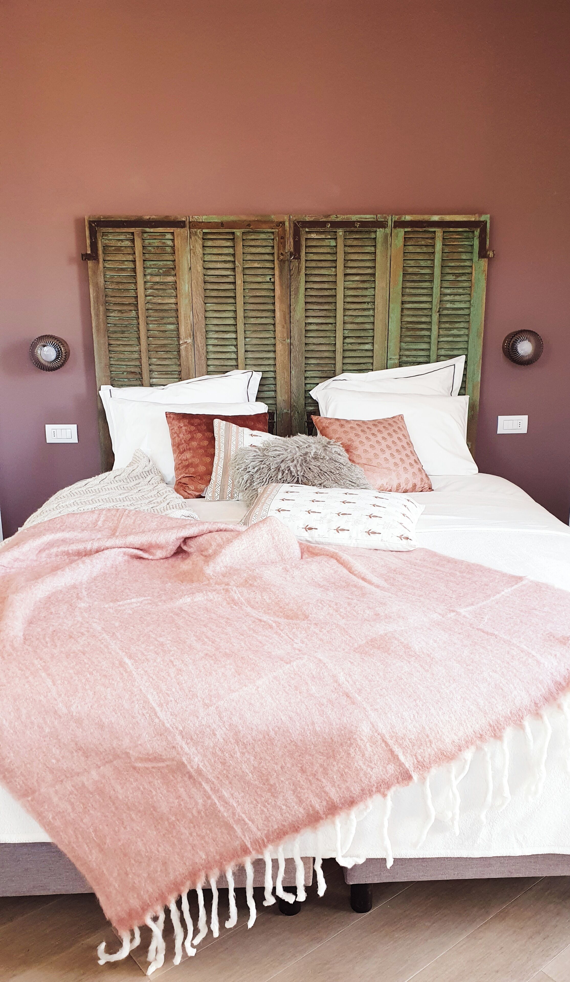 Ein Bett mit einer rosa Decke, weißen Kissen und einem hölzernen Kopfteil.