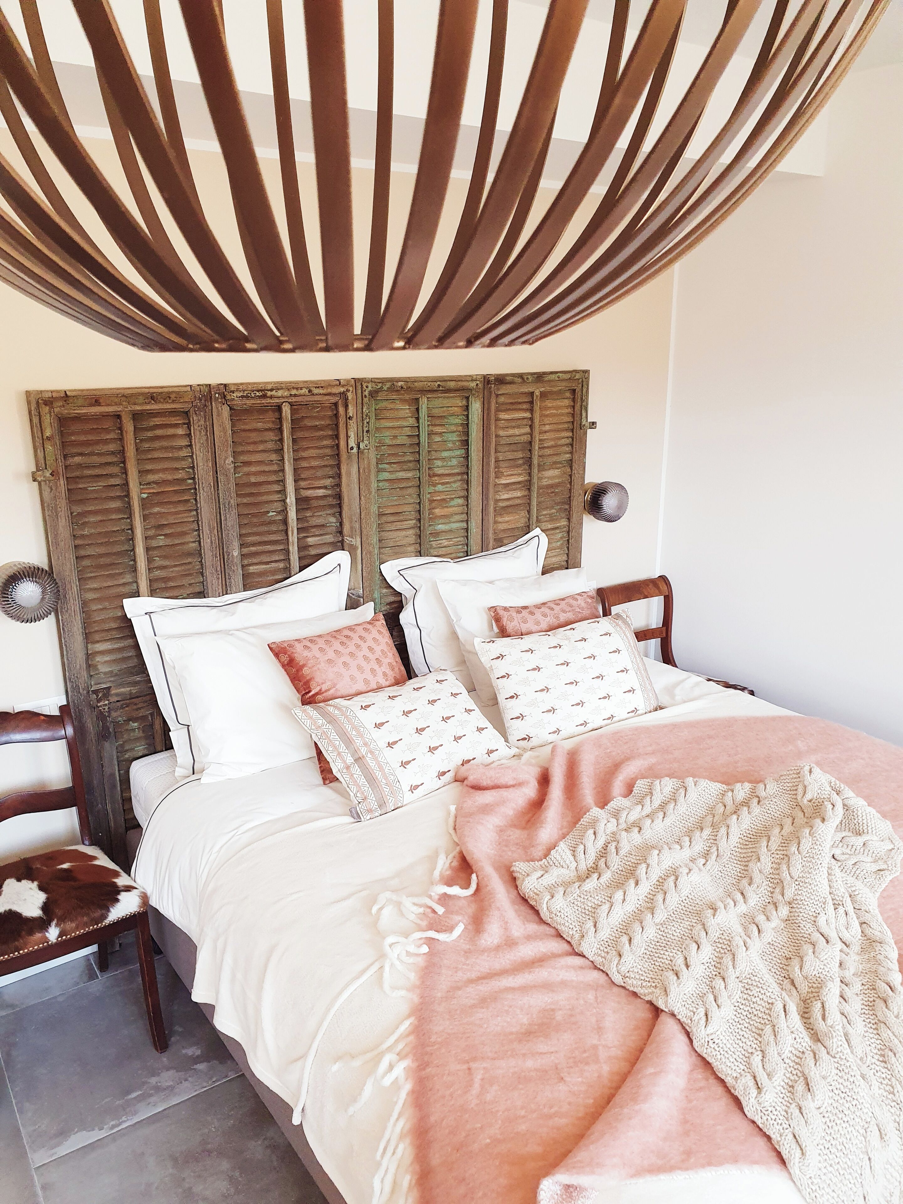 A bed with a wooden headboard, multiple pillows, and a knitted throw blanket.